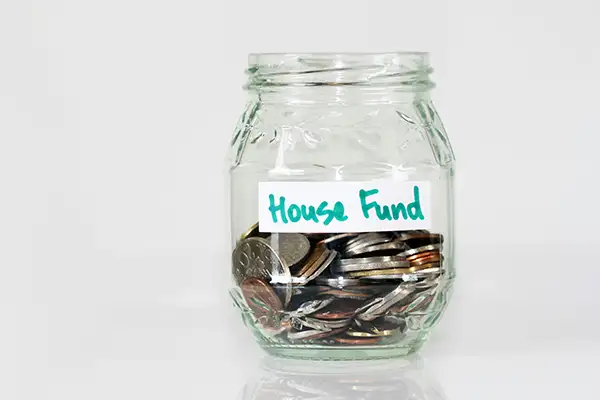 glass jar with coins in it and a hand-written label saying "house fund"
